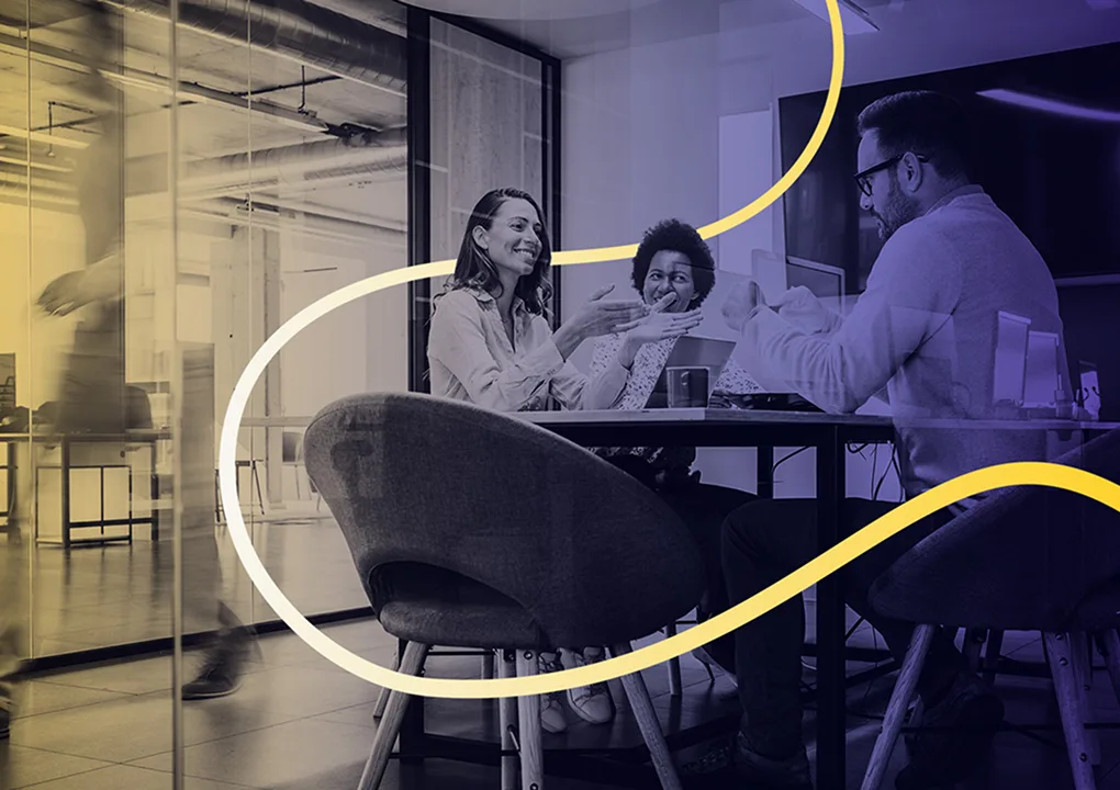 Three colleagues around a desk.