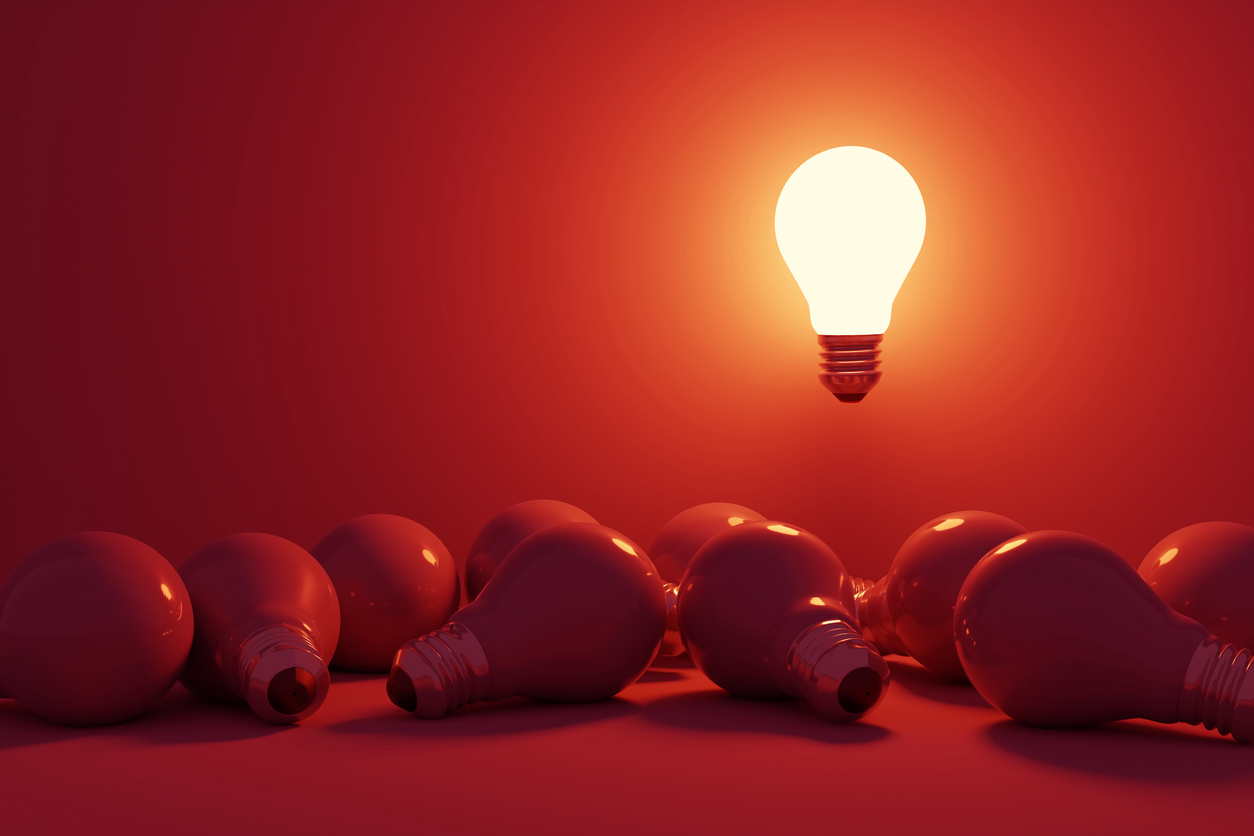 bright lightbulb standing our from other darker lightbulbs.