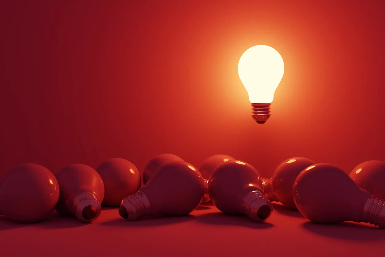 bright lightbulb standing our from other darker lightbulbs.